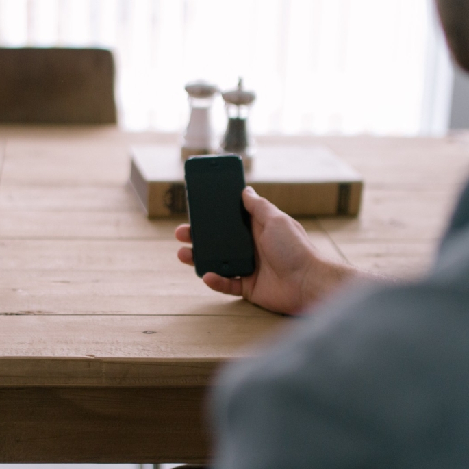 cropped-person-smartphone-office-table